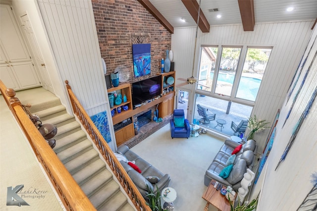 carpeted living area with recessed lighting, visible vents, stairway, lofted ceiling with beams, and brick wall