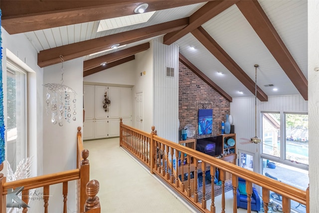 corridor with visible vents, beamed ceiling, and an upstairs landing