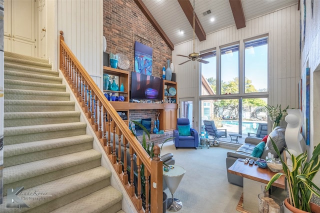 living room with carpet floors, beam ceiling, visible vents, a brick fireplace, and high vaulted ceiling