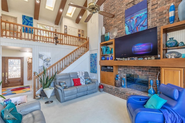 carpeted living room featuring brick wall, stairway, beamed ceiling, a high ceiling, and a brick fireplace