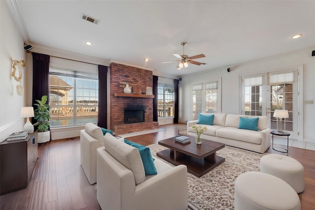 living room with ornamental molding, a fireplace, wood finished floors, and visible vents