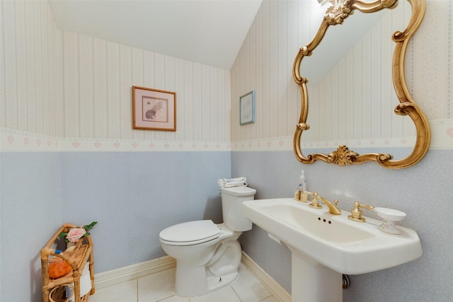 half bathroom featuring lofted ceiling, baseboards, toilet, and tile patterned floors