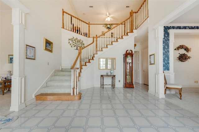 staircase featuring a towering ceiling and ornate columns