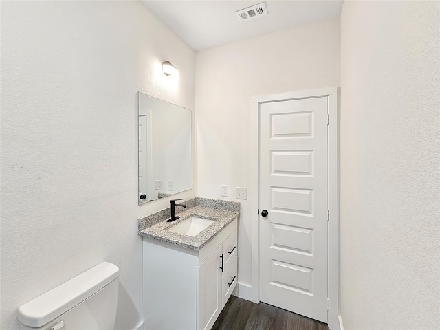 bathroom featuring toilet, wood finished floors, vanity, and visible vents