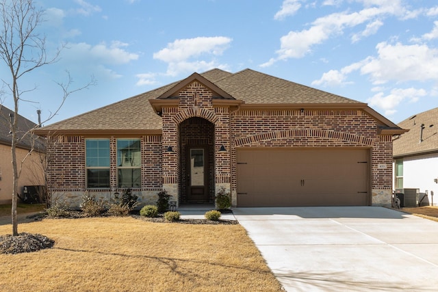 french country style house featuring an attached garage, a shingled roof, concrete driveway, and brick siding