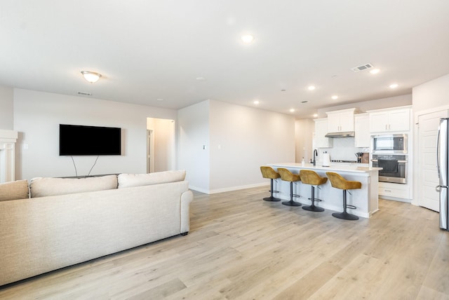 living room featuring baseboards, recessed lighting, visible vents, and light wood-style floors