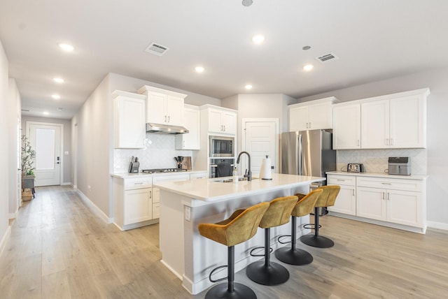 kitchen with stainless steel appliances, a sink, visible vents, and under cabinet range hood