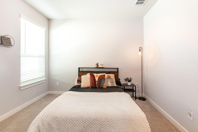 bedroom with visible vents, light carpet, and baseboards