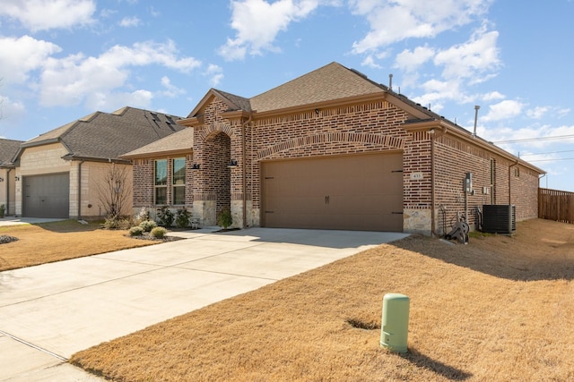 view of front of home featuring a garage, central AC, brick siding, a shingled roof, and driveway