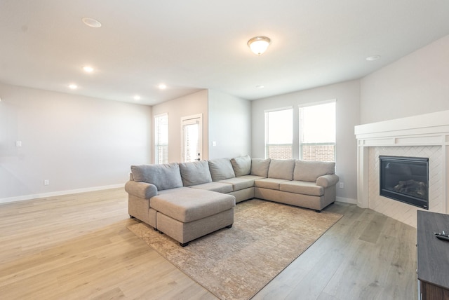 living area featuring light wood-style flooring, baseboards, a tiled fireplace, and recessed lighting