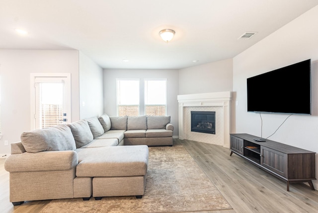 living room featuring light wood-type flooring, a fireplace, visible vents, and recessed lighting