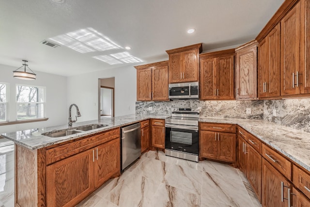 kitchen featuring tasteful backsplash, brown cabinetry, appliances with stainless steel finishes, a peninsula, and a sink