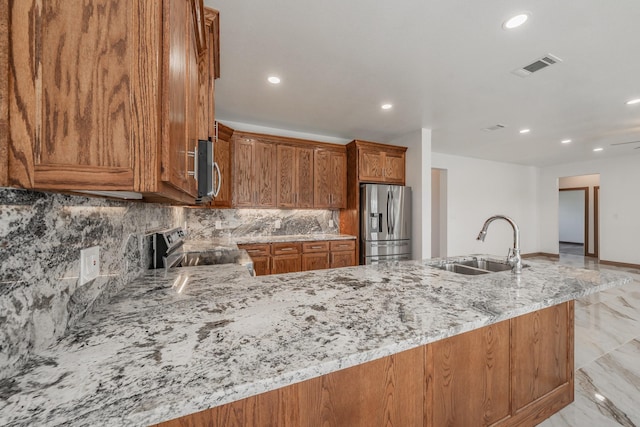 kitchen featuring appliances with stainless steel finishes, a sink, visible vents, and light stone countertops