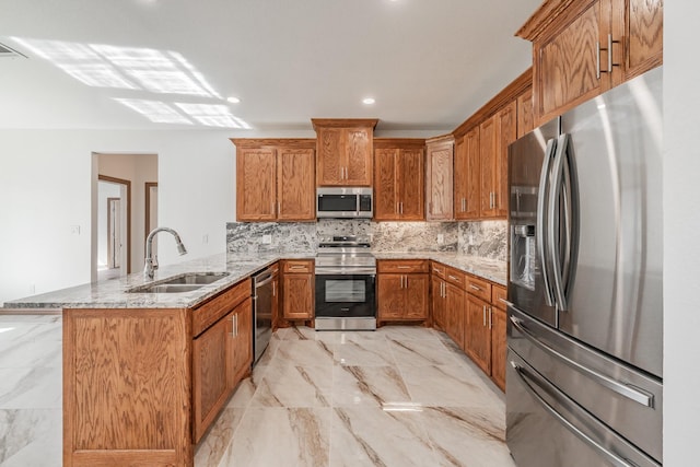 kitchen featuring brown cabinetry, a peninsula, marble finish floor, stainless steel appliances, and a sink