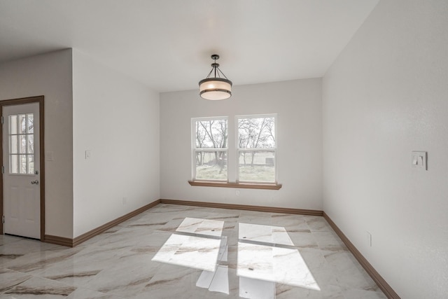 unfurnished dining area with marble finish floor and baseboards