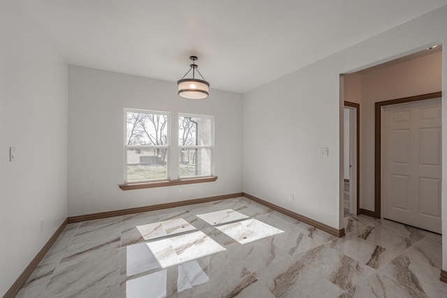 unfurnished dining area with marble finish floor and baseboards