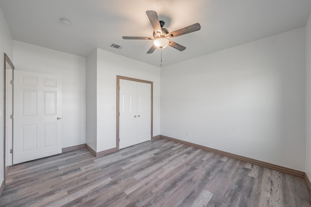 unfurnished bedroom with light wood finished floors, baseboards, visible vents, and a closet