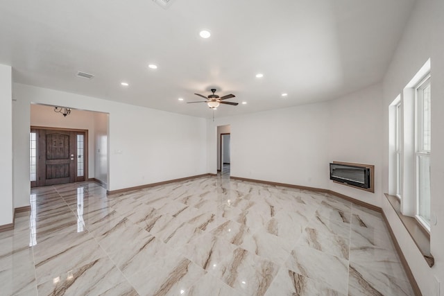 unfurnished living room with recessed lighting, visible vents, baseboards, marble finish floor, and a glass covered fireplace