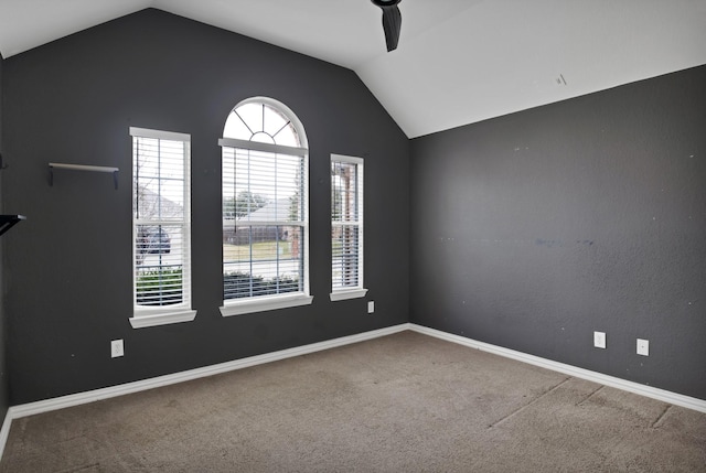 carpeted empty room featuring ceiling fan, baseboards, and vaulted ceiling