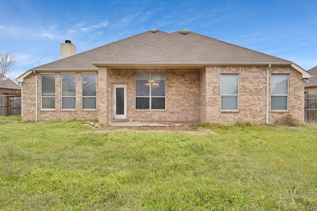 back of property with a yard, brick siding, fence, and a chimney