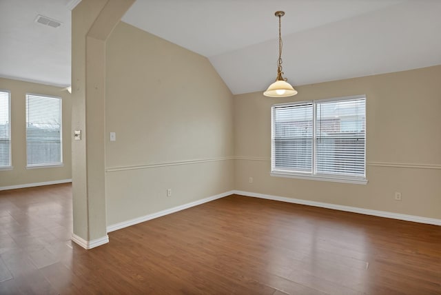 empty room with lofted ceiling, visible vents, arched walkways, and dark wood-type flooring