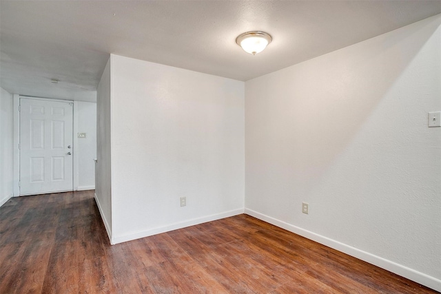 empty room with dark wood-style flooring and baseboards