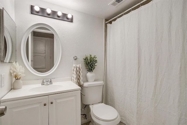 bathroom featuring toilet, a textured wall, visible vents, and vanity