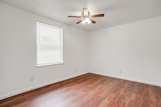 spare room featuring wood finished floors, a wealth of natural light, and baseboards