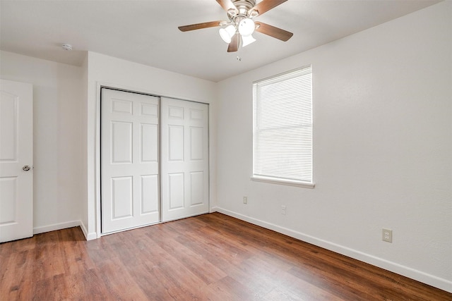 unfurnished bedroom with a ceiling fan, a closet, baseboards, and wood finished floors