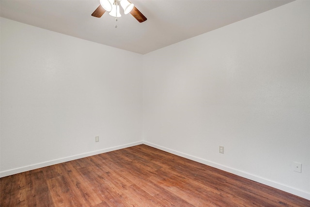 empty room with wood finished floors, a ceiling fan, and baseboards