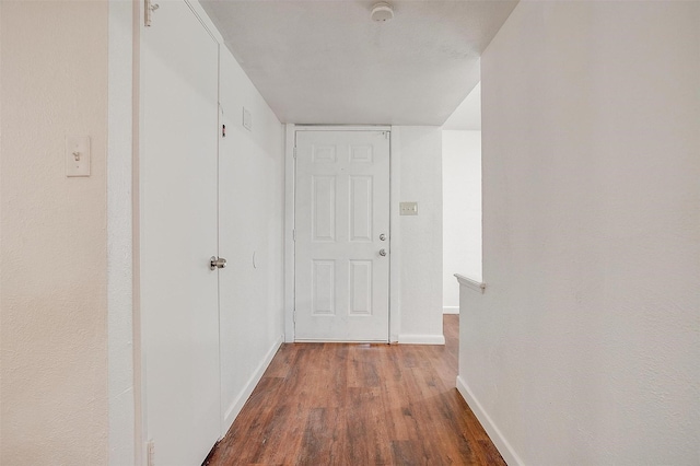 corridor featuring baseboards and wood finished floors