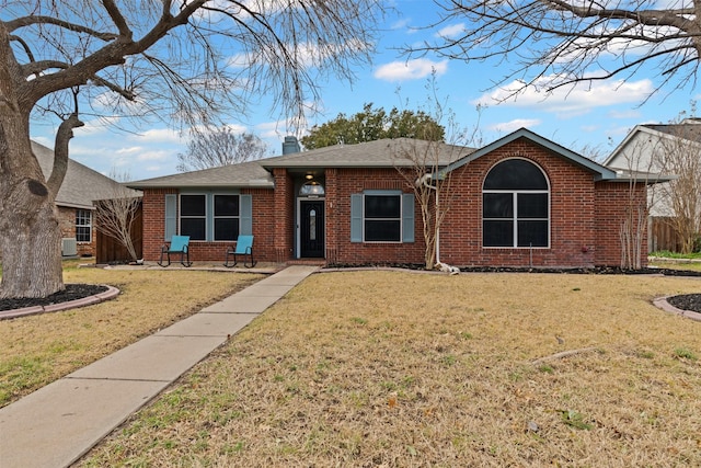 ranch-style home with roof with shingles, brick siding, a chimney, and a front lawn