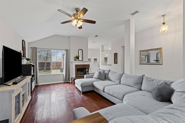 living room featuring lofted ceiling, visible vents, baseboards, a brick fireplace, and dark wood finished floors