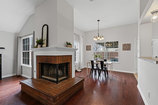 living area featuring a fireplace, baseboards, vaulted ceiling, and wood finished floors