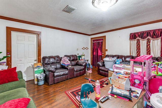 living room with visible vents, a textured ceiling, wood finished floors, and ornamental molding