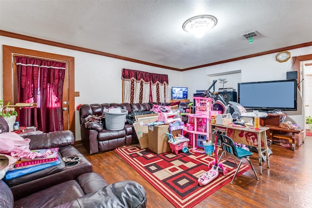 living area with visible vents, a textured ceiling, wood finished floors, and crown molding