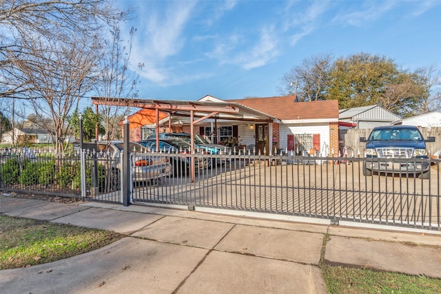 view of front of property with a fenced front yard, driveway, brick siding, and a gate