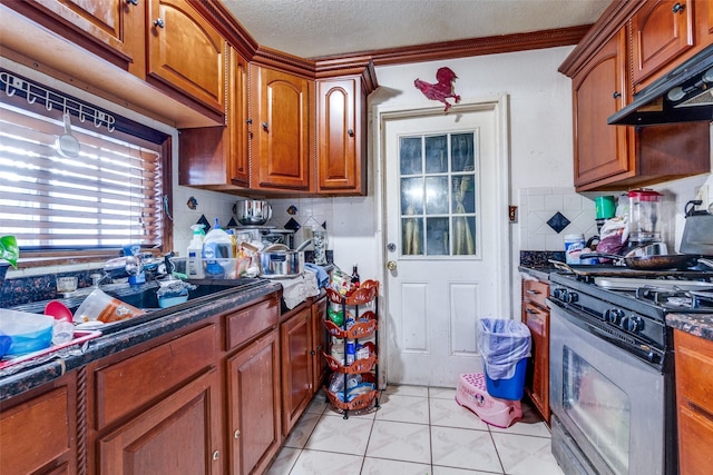 kitchen featuring under cabinet range hood, tasteful backsplash, a textured ceiling, brown cabinetry, and stainless steel range with gas stovetop