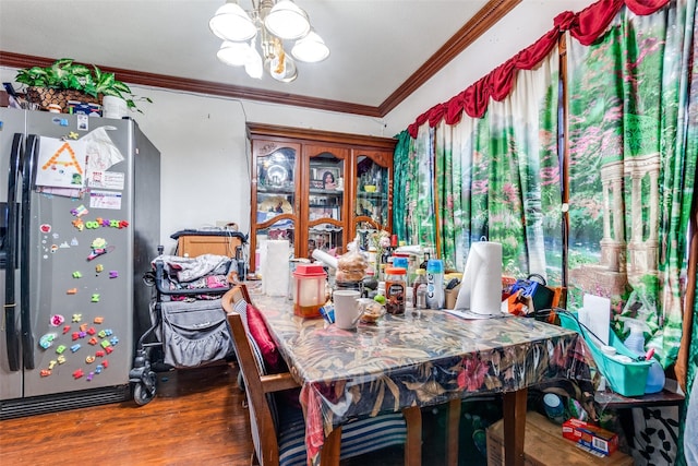 dining area with wood finished floors, a notable chandelier, and ornamental molding