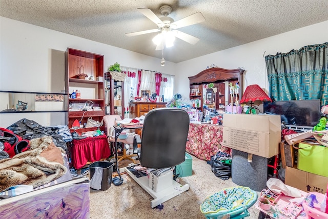 carpeted home office with a textured ceiling and ceiling fan