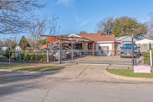 view of front of property featuring driveway, brick siding, and a fenced front yard