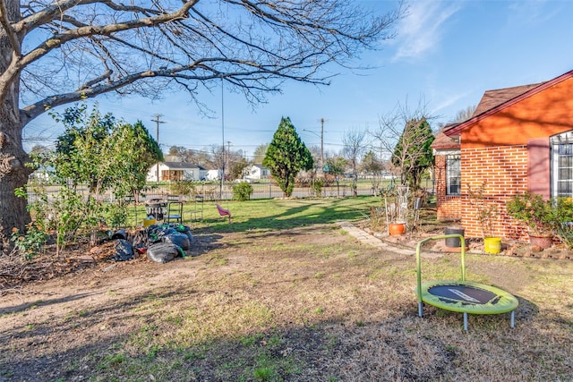 view of yard with a trampoline and fence