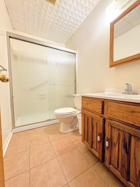 bathroom with a stall shower, vanity, toilet, and tile patterned floors