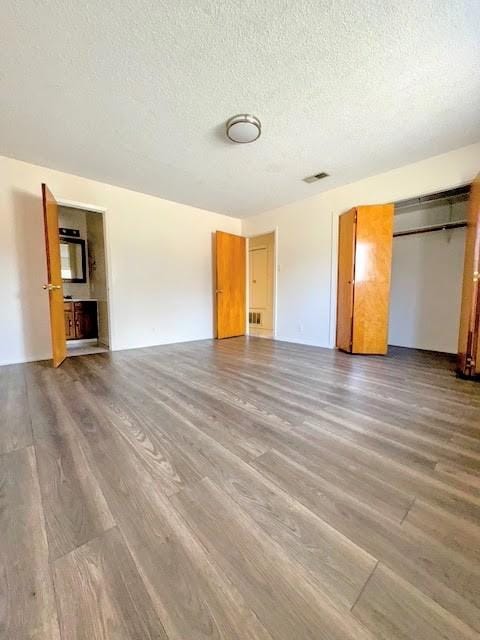 interior space featuring a closet, a textured ceiling, visible vents, and wood finished floors