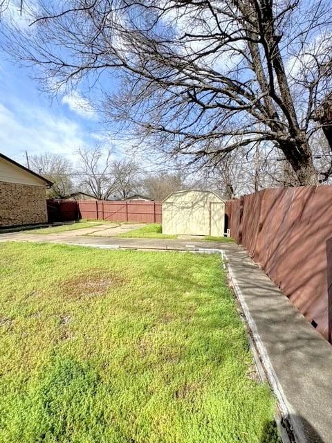 view of yard with an outdoor structure, fence, and a storage unit