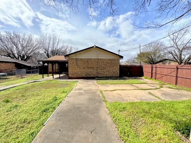 view of side of property featuring a yard, brick siding, and fence