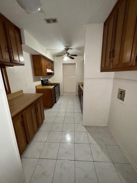 kitchen featuring electric stove, light tile patterned floors, visible vents, ceiling fan, and under cabinet range hood