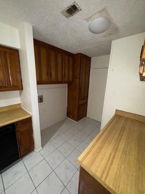 kitchen with a textured ceiling, visible vents, and dishwasher