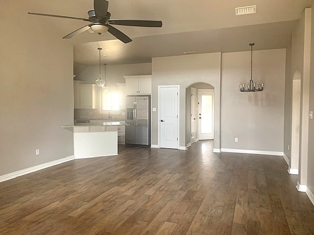 kitchen with arched walkways, open floor plan, stainless steel fridge, and visible vents