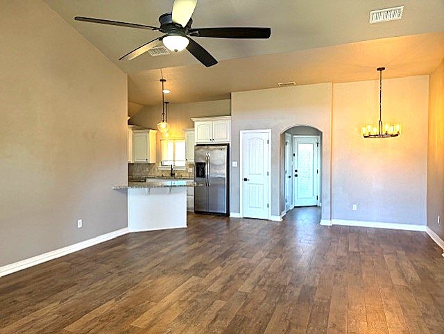 kitchen featuring dark wood-style floors, arched walkways, visible vents, white cabinets, and stainless steel fridge with ice dispenser